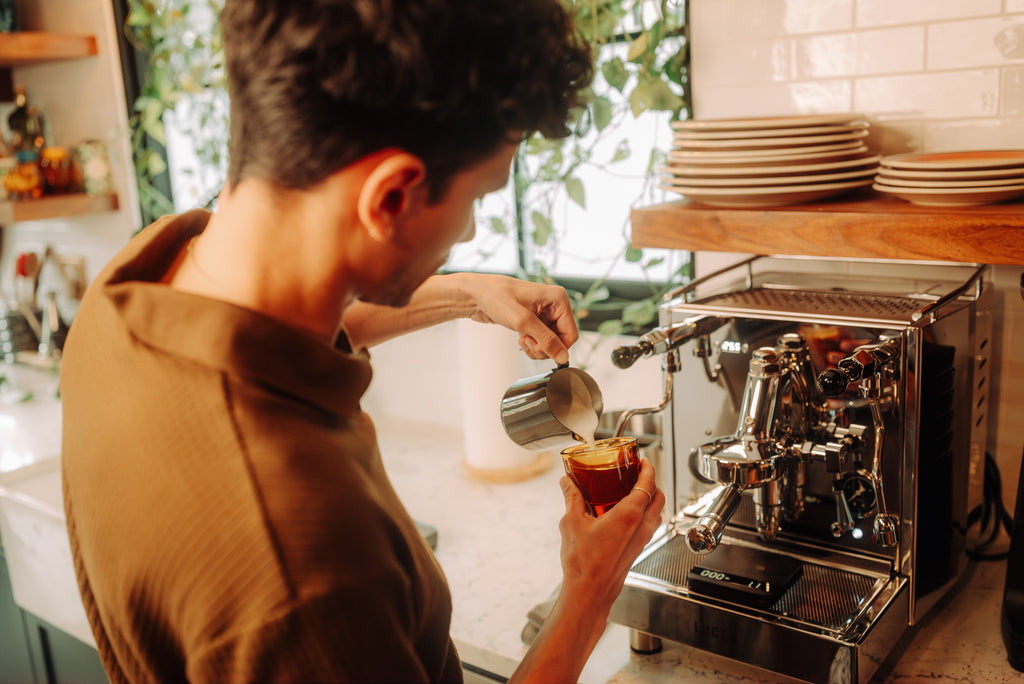 over the shoulder view of a person pouring latte art lifestyle by clive coffee